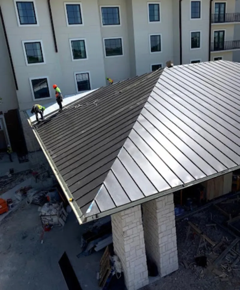 Crew installing standing seam metal roof panels on a commercial project in Central Falls